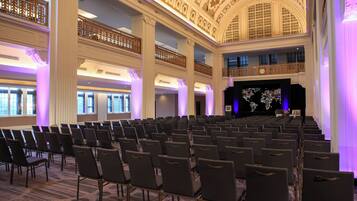 A large hall with rows of chairs, a balcony, and a stage with a screen.