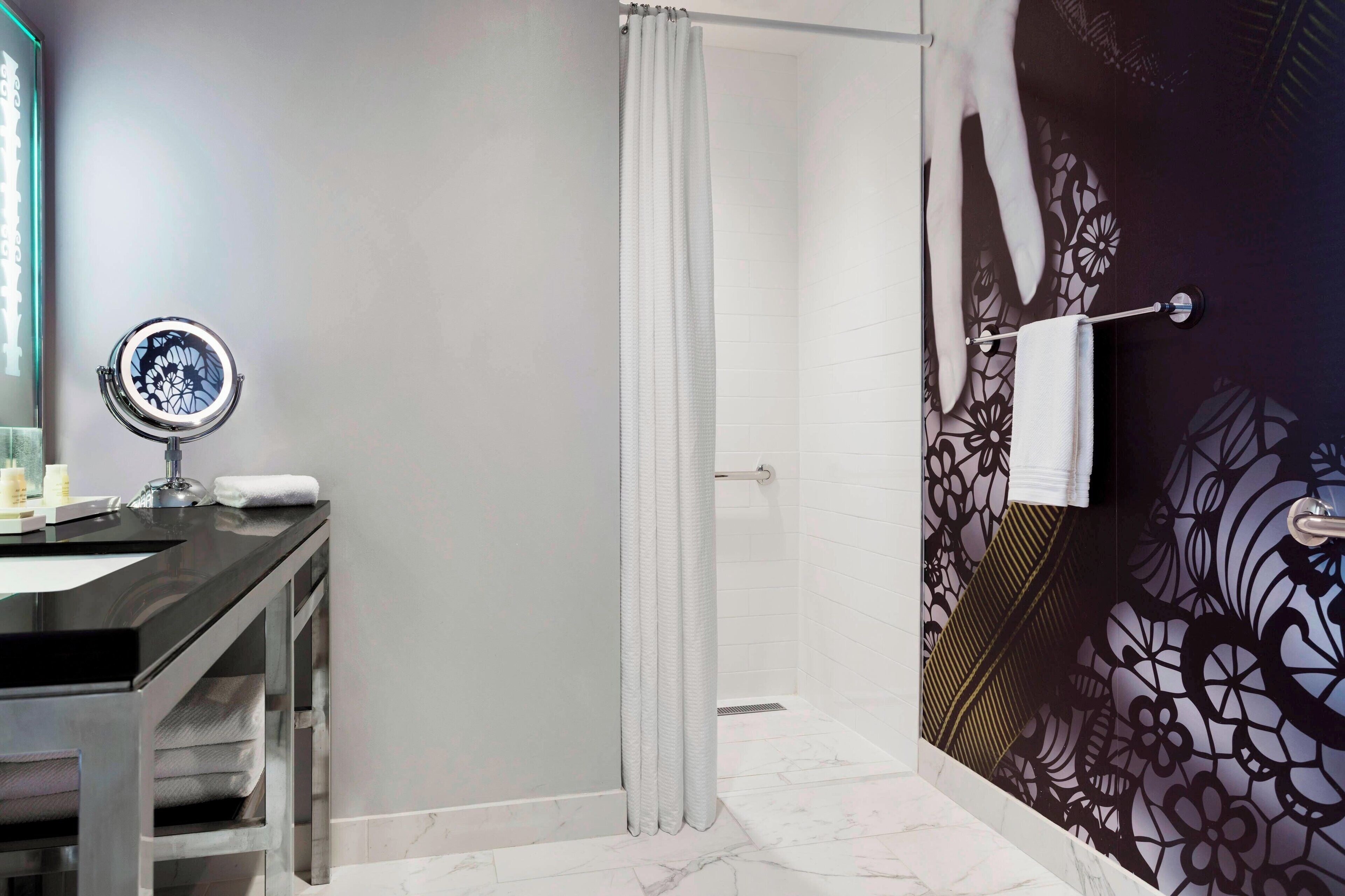 A bathroom with a shower, a sink with a mirror, and a towel rack.