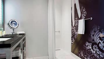 A bathroom with a shower, a sink with a mirror, and a towel rack.