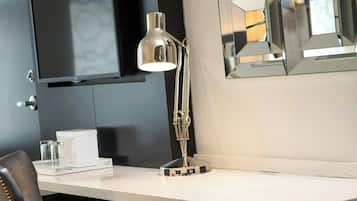 A modern room with a desk, chair, lamp, and a flat-screen TV mounted on the wall.