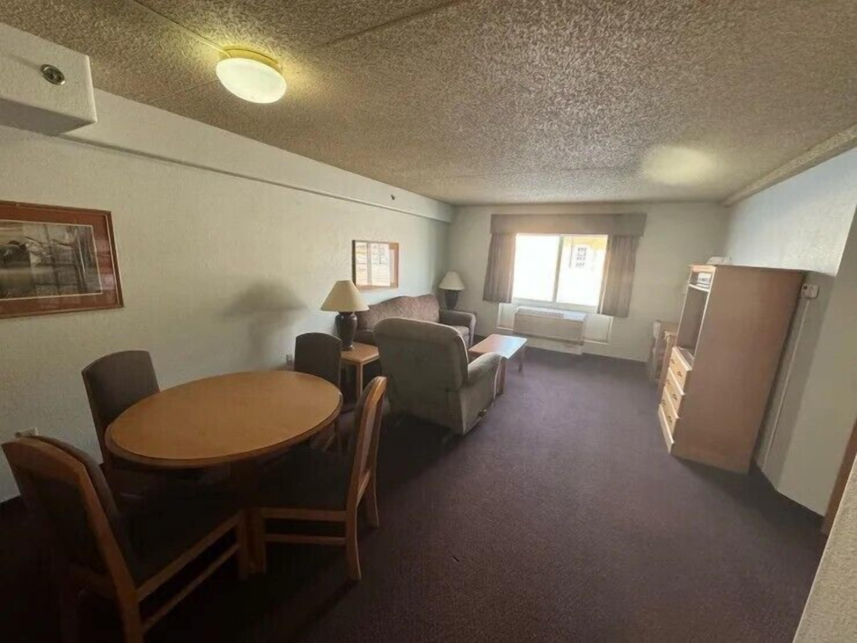 A compact living space with a dining area, a sofa, a lamp, and a window.
