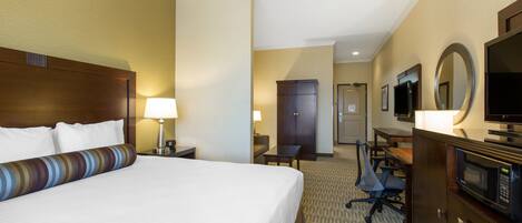 A hotel room with a large bed, a desk, a chair, a television, and a microwave.