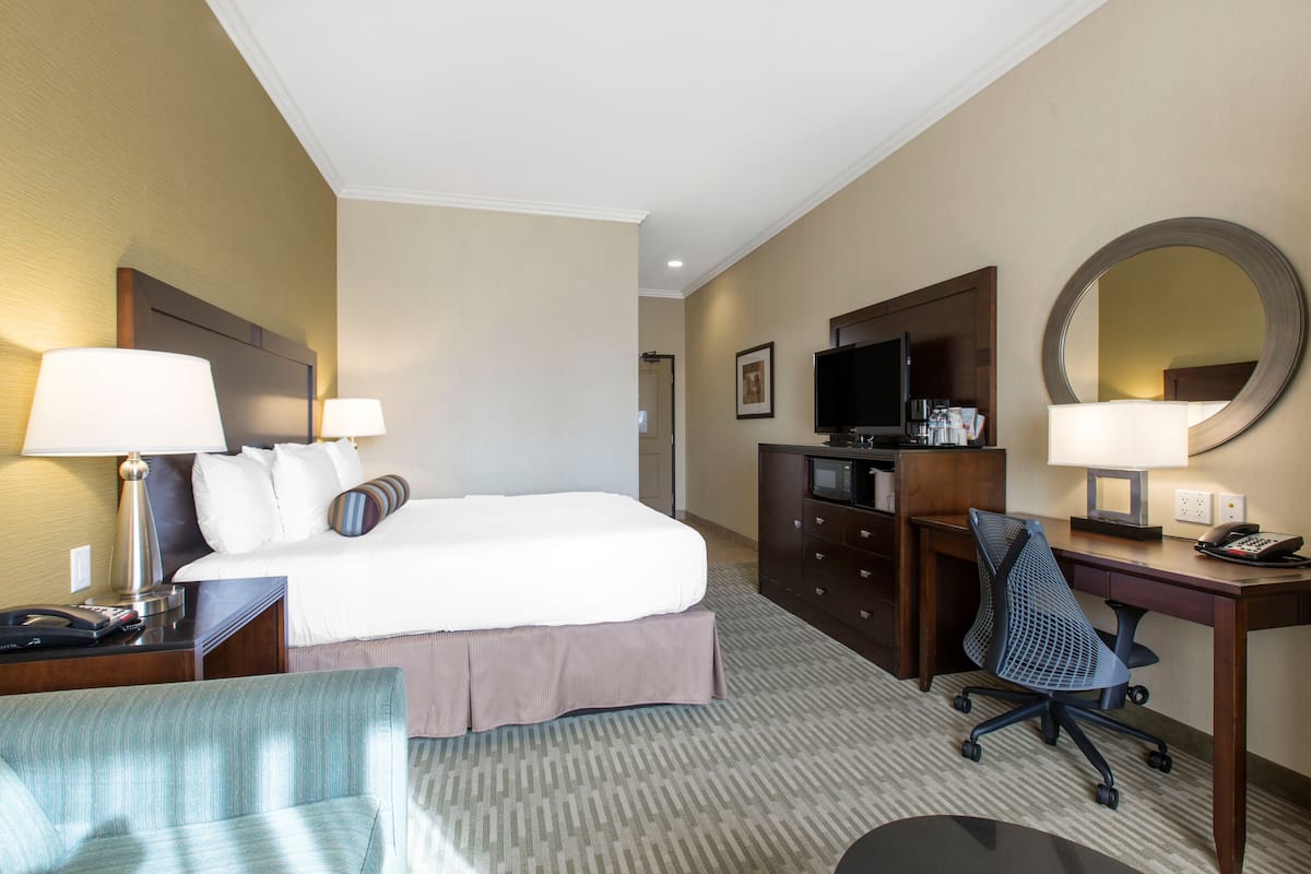 Een hotelkamer met een bed, bureau, stoel, bureaulamp en een grote spiegel.