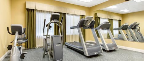 Un gimnasio con cintas de correr, una elíptica y una bicicleta estática.