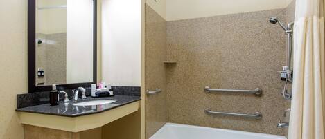 A bathroom with a sink, mirror, and shower area.