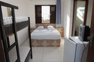 A bedroom with a bed, a window, a television, and a refrigerator.
