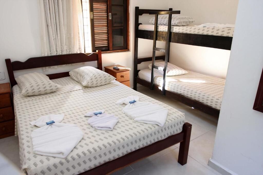 A room with a wooden bed, a nightstand, and a bunk bed.