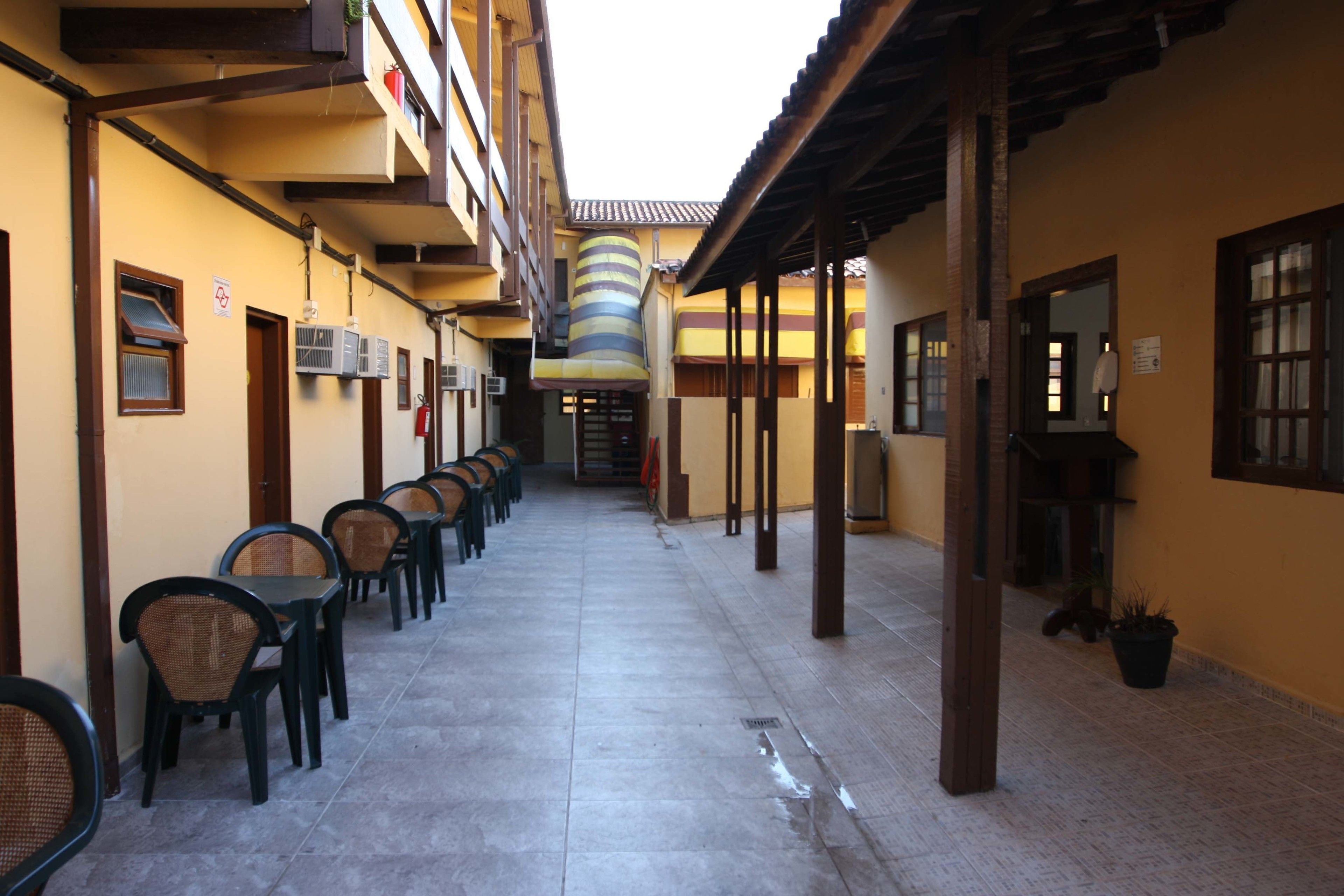 A corridor with multiple tables and chairs, a tiled floor, and a ceiling with a striped pattern.