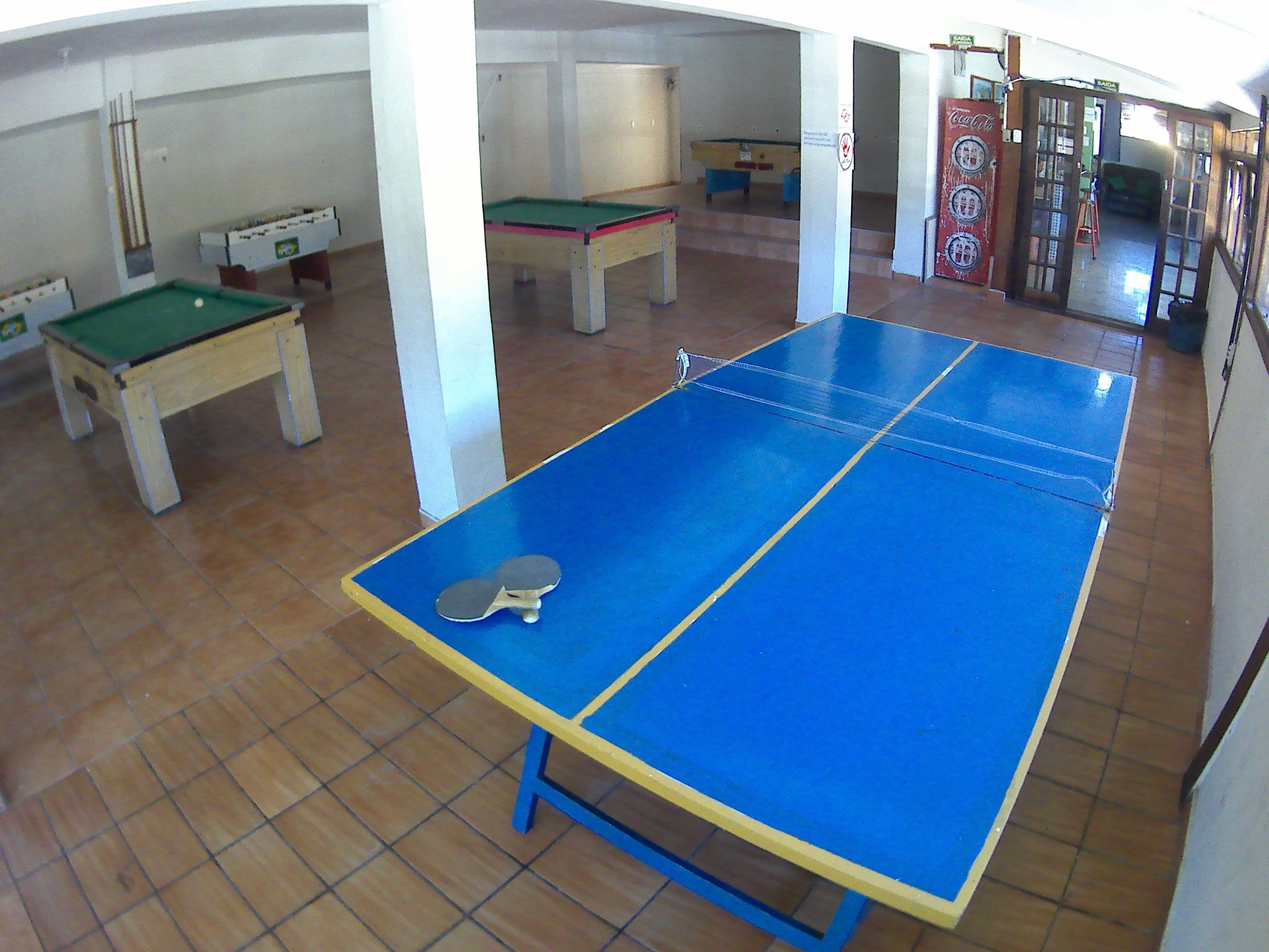 Una habitación con mesa de ping pong, dos mesas de fútbolín y una mesa de billar.