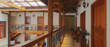 A spacious hallway with wooden railings, a patterned floor, and a skylight.