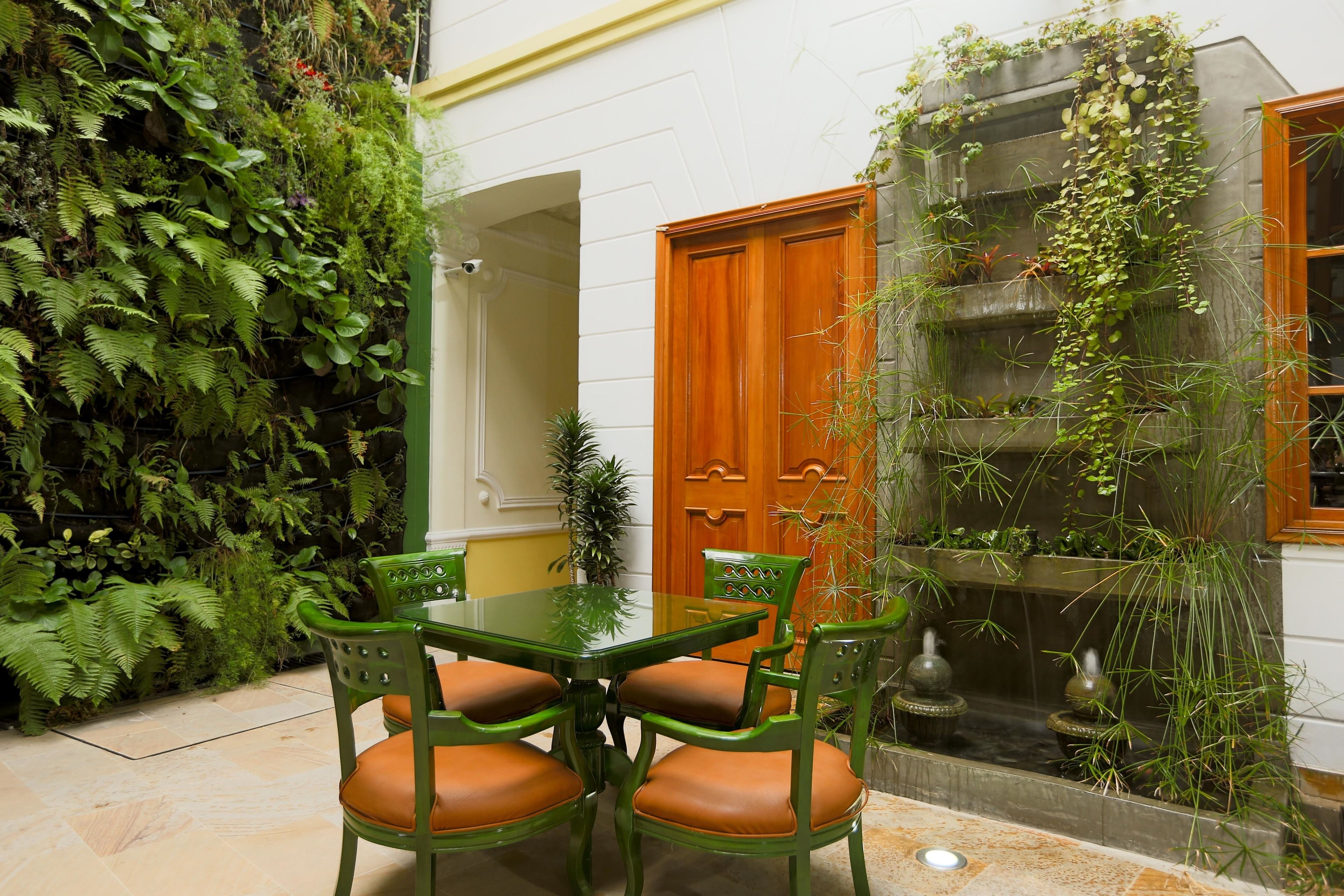 Un comedor con mesa y sillas, una puerta de madera y una pared cubierta de follaje.