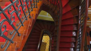 A wooden staircase with red carpeted steps and black wrought iron railings.