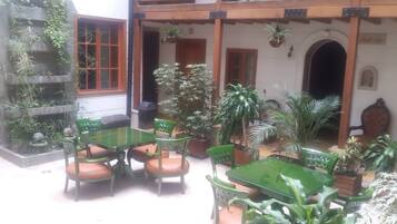 A patio area with a table and chairs, surrounded by potted plants and a wooden pergola.