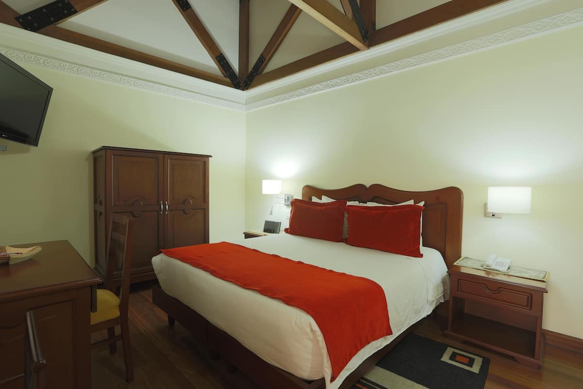 Ein ordentlich eingerichtetes Hotelzimmer mit Bett, Nachttisch, Schreibtisch und Kleiderschrank.