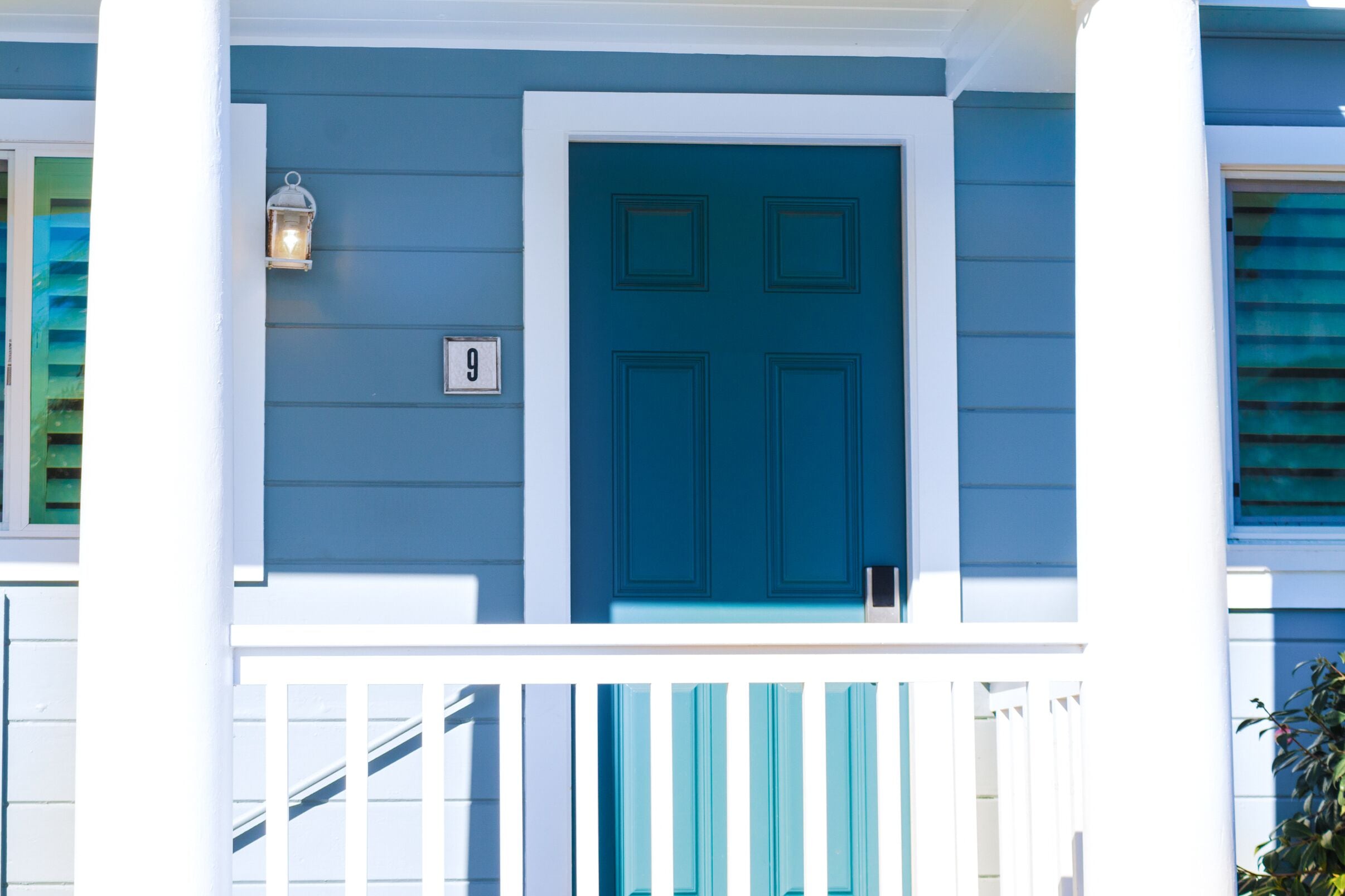 A blue door with a white frame, a white number '9' sign, and a white railing.