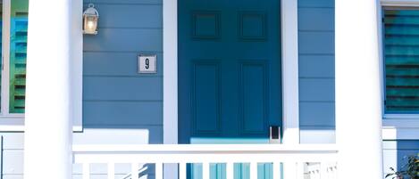 A blue door with a white frame, a white number '9' sign, and a white railing.