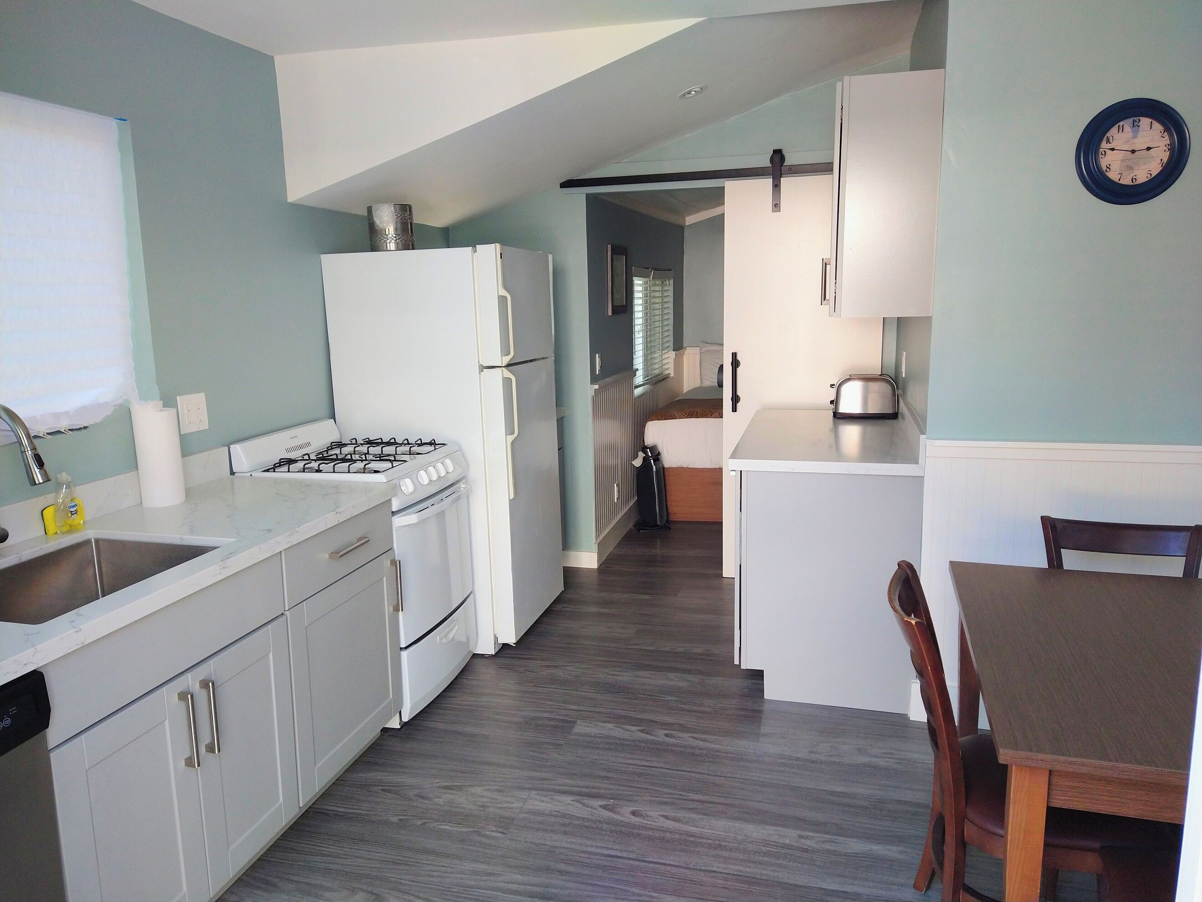 A compact kitchen with white appliances, a sink, and a dining area with a table and chairs.