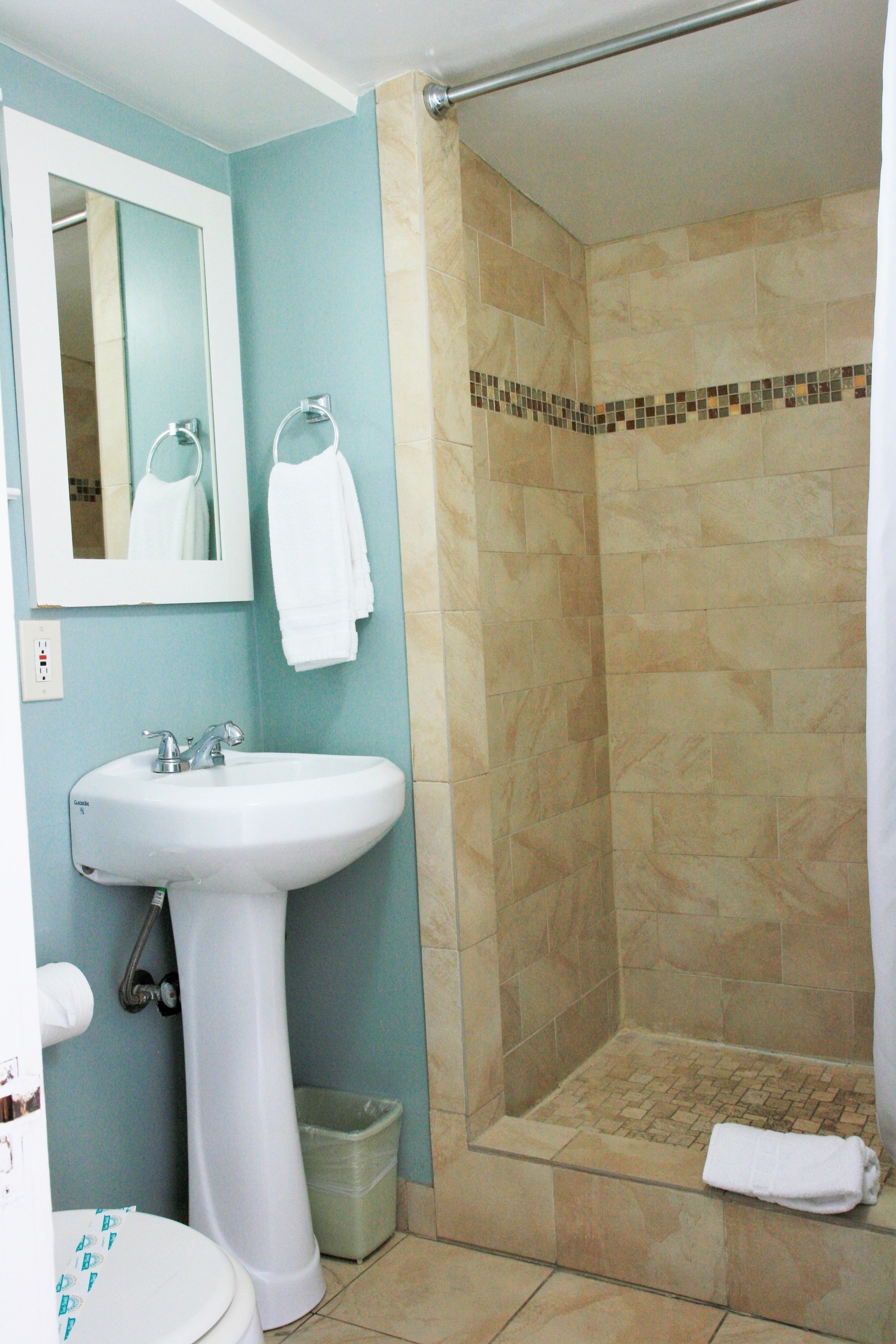 A bathroom with a sink, mirror, and shower.