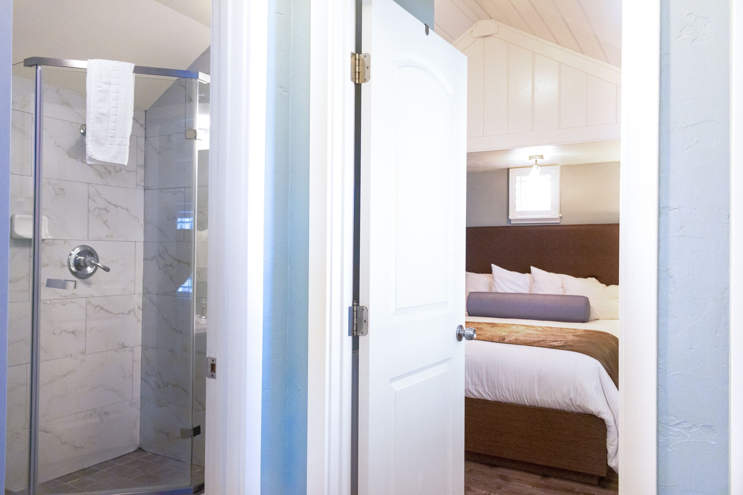 A room with a shower, a bed, and a window.