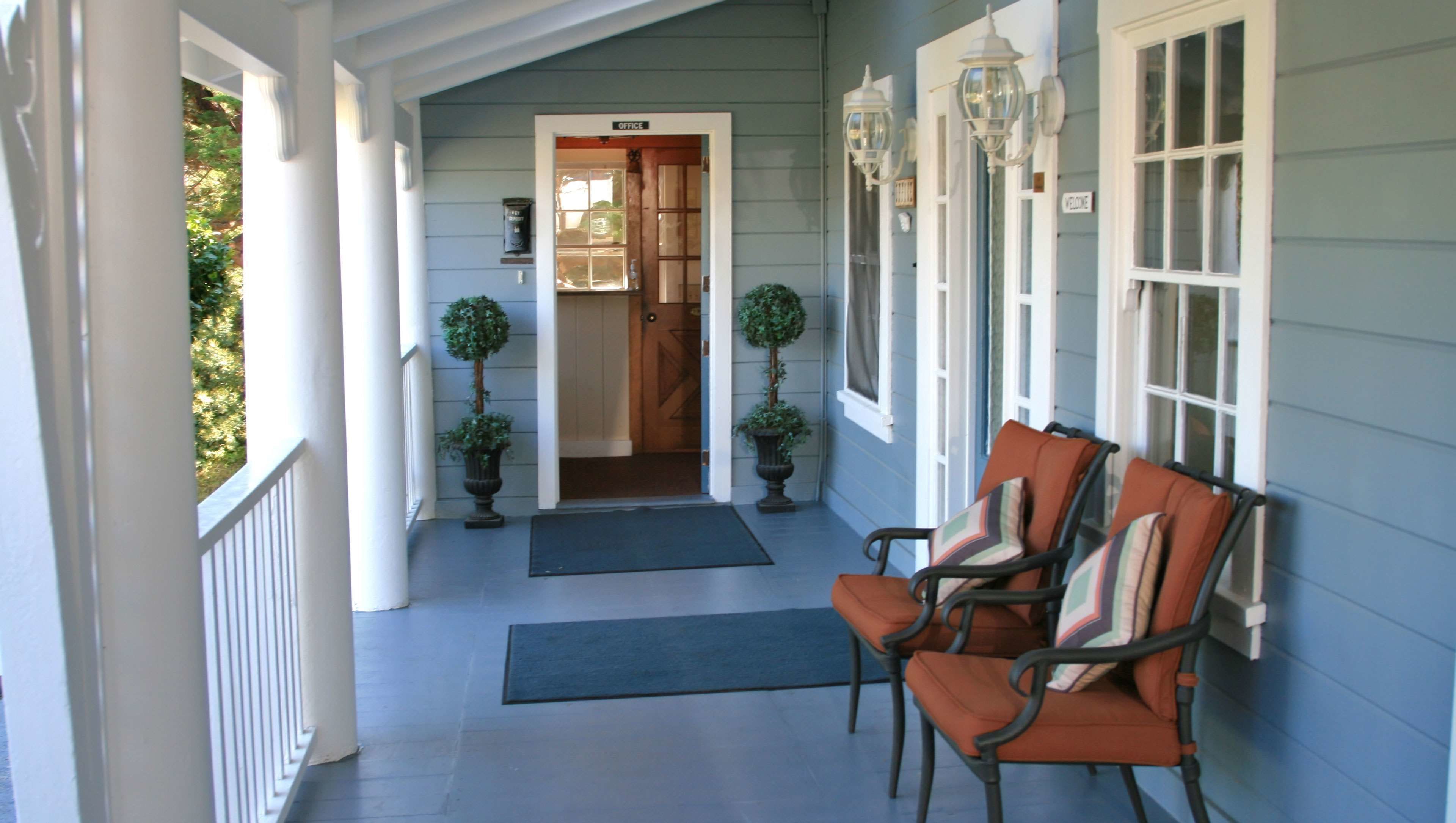 A porch with a bench, a door labeled "OFFICE," and two potted plants.