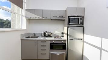 A compact kitchen with a built-in oven, microwave, and refrigerator.