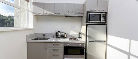 A compact kitchen with a built-in oven, microwave, and refrigerator.
