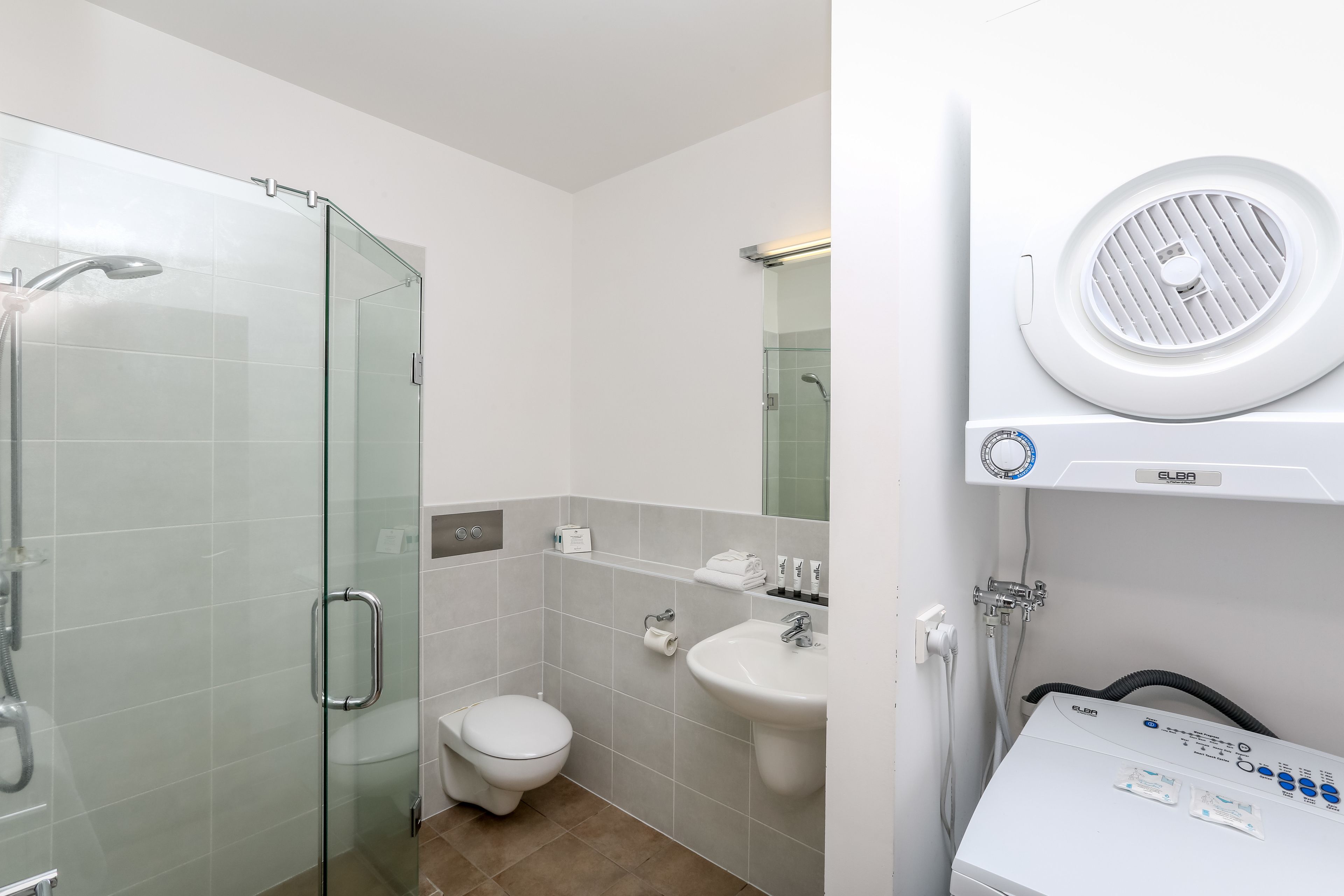 A modern bathroom with a glass-enclosed shower, a white toilet, a sink, and a steam shower unit.