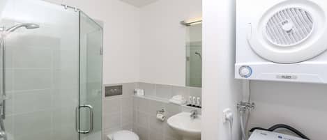 A modern bathroom with a glass-enclosed shower, a white toilet, a sink, and a steam shower unit.