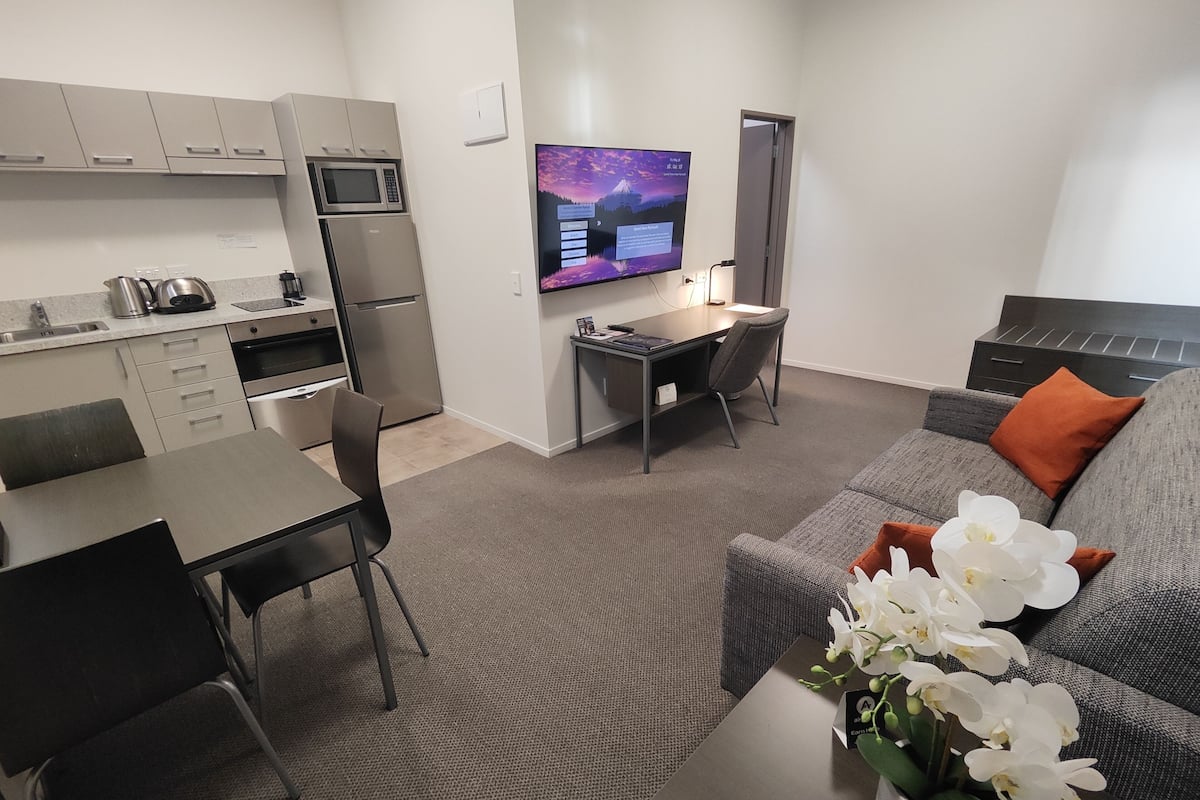 A compact living space with a kitchenette, a dining area, a workspace, and a seating area with a sofa and a coffee table.