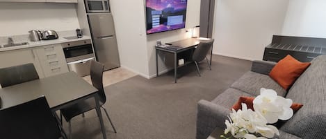 A compact living space with a kitchenette, a dining area, a workspace, and a seating area with a sofa and a coffee table.