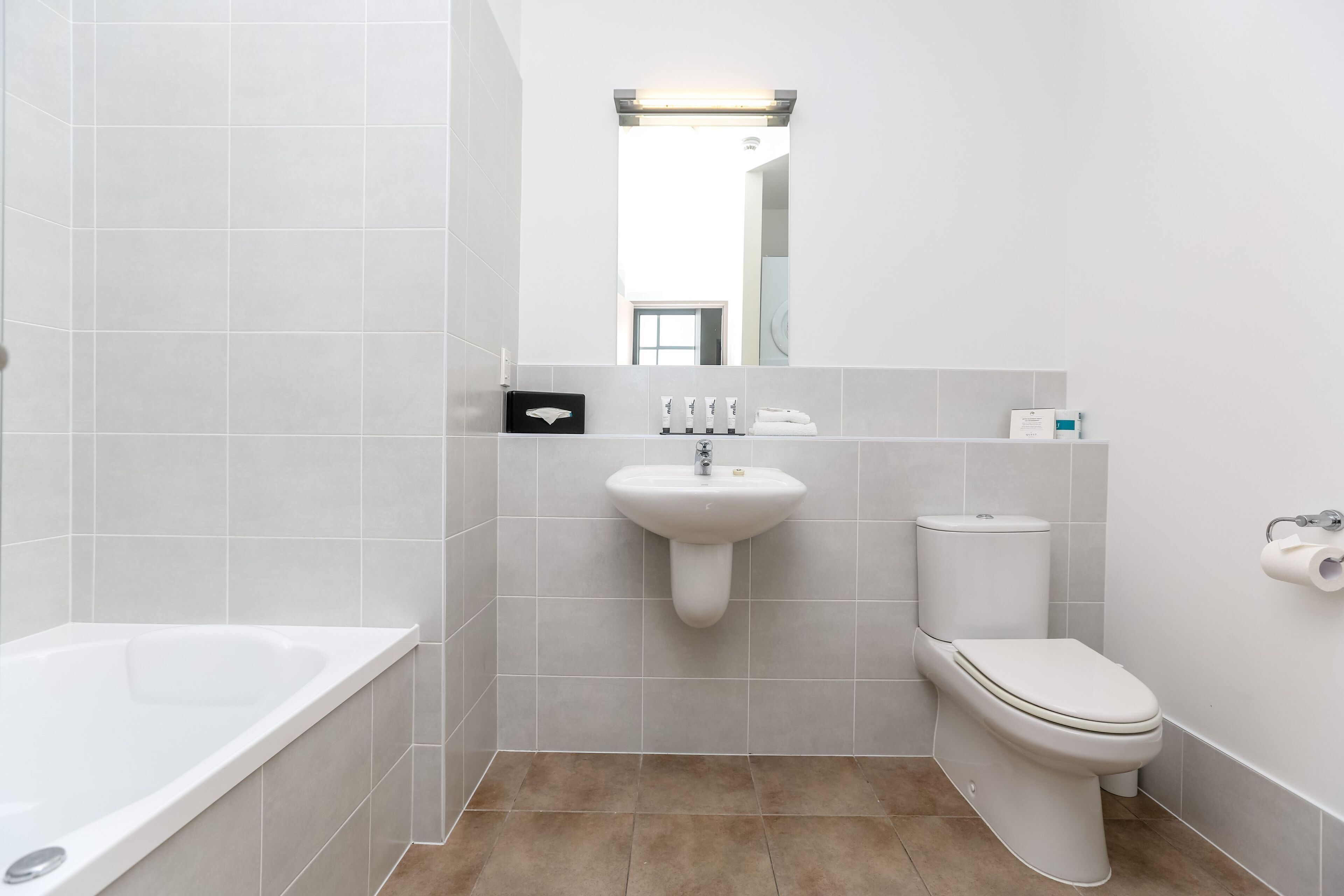 Un bagno moderno con vasca, lavandino, water e specchio.