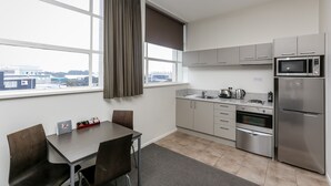 A modern kitchen with a dining area, large windows, and a view of the city.