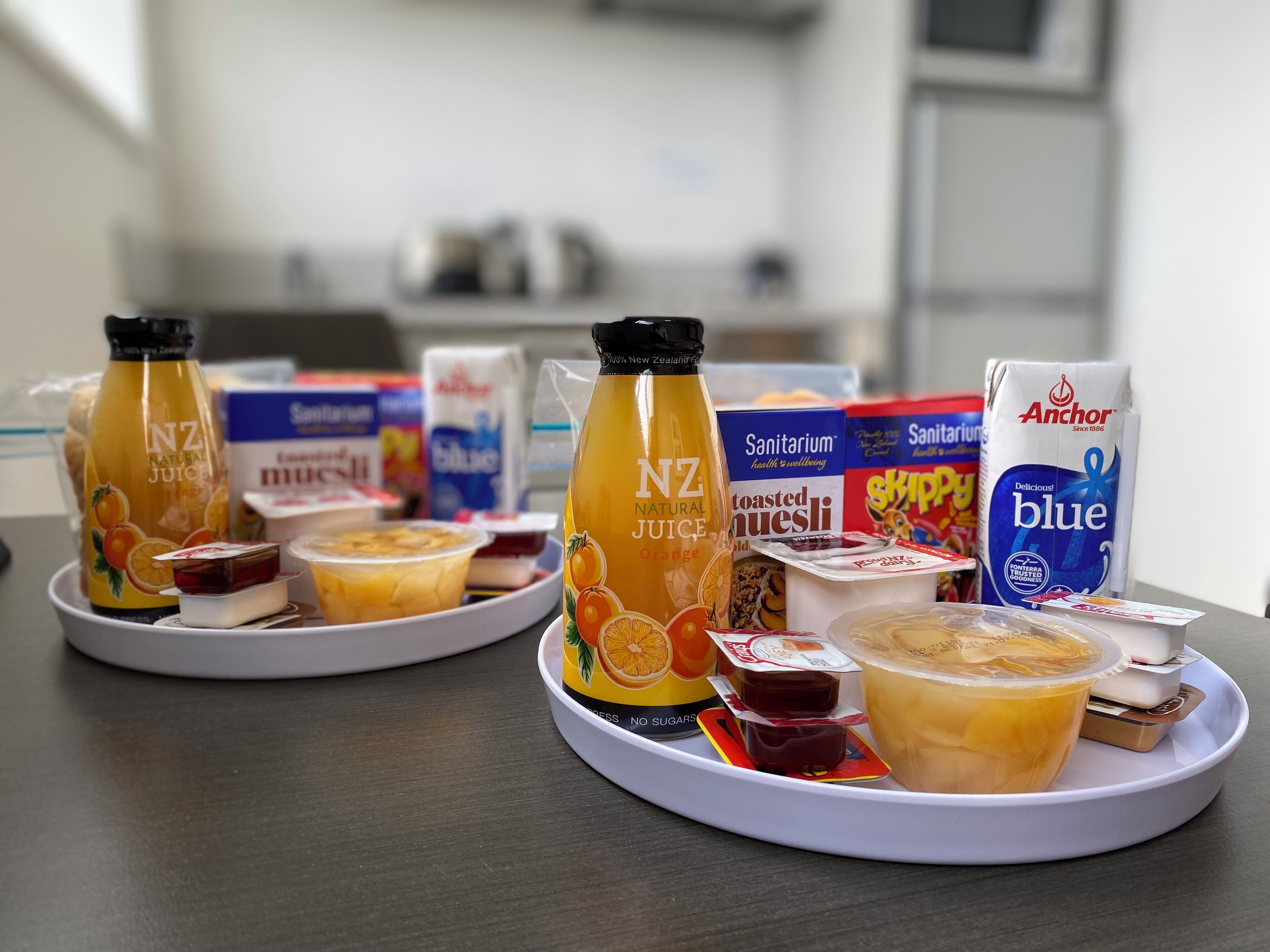 Un plateau de petit-déjeuner comprenant du jus de fruits NZ Natural, des boissons santé de la marque Sanitariaum et du lait en poudre Anchor Blue.