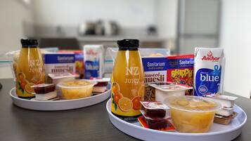 Un plateau de petit-déjeuner comprenant du jus de fruits NZ Natural, des boissons santé de la marque Sanitariaum et du lait en poudre Anchor Blue.