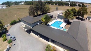 A hotel with a swimming pool, a covered parking area, and a view of the surrounding landscape. - Thornton Lodge Motel (Waipukurau)