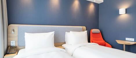 Habitación de hotel con cama, una silla, mesita de noche y una lámpara de pared.