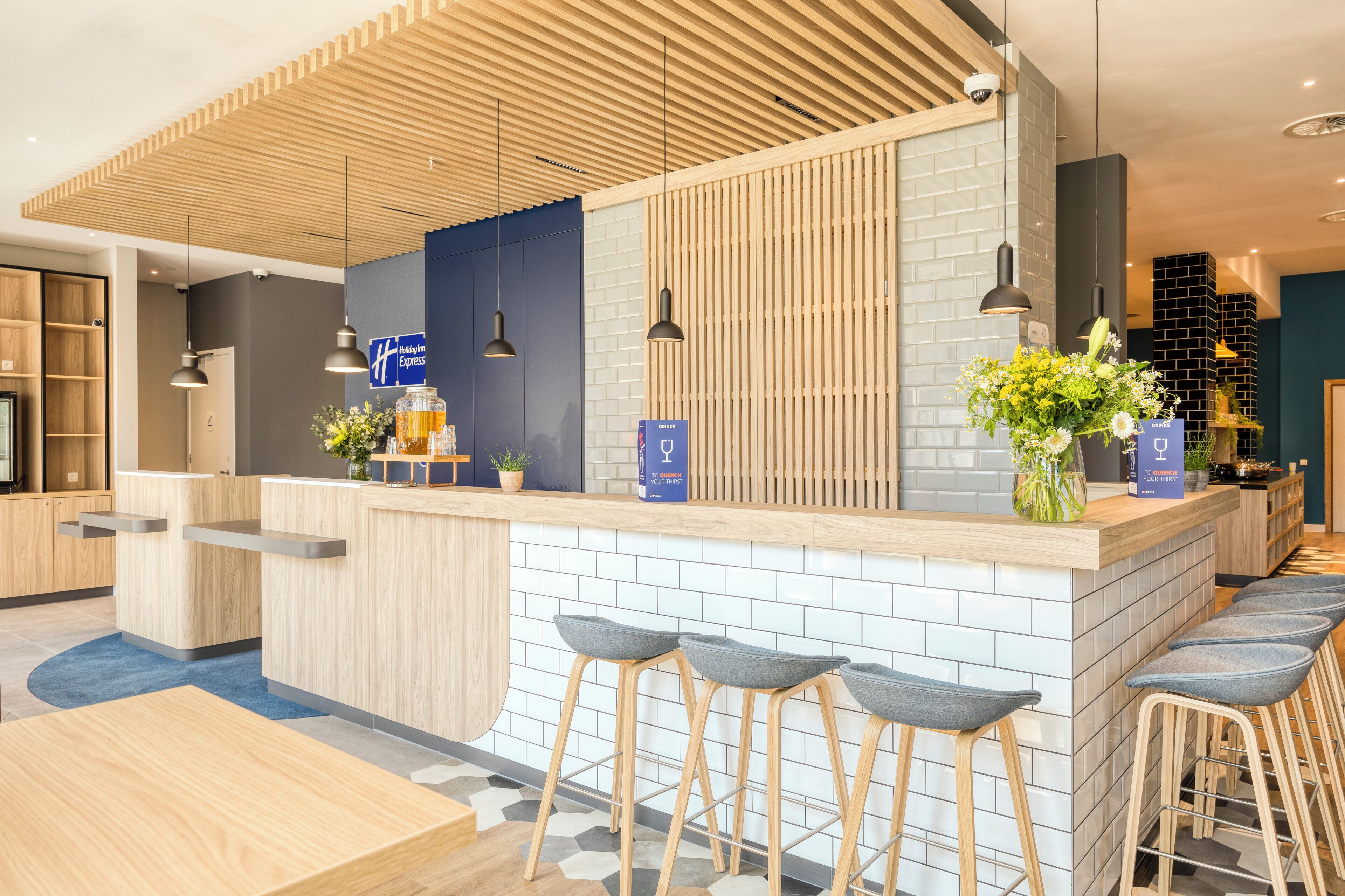 A modern reception area with a wooden counter, bar stools, and a blue sign.