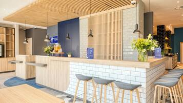 A modern reception area with a wooden counter, bar stools, and a blue sign.