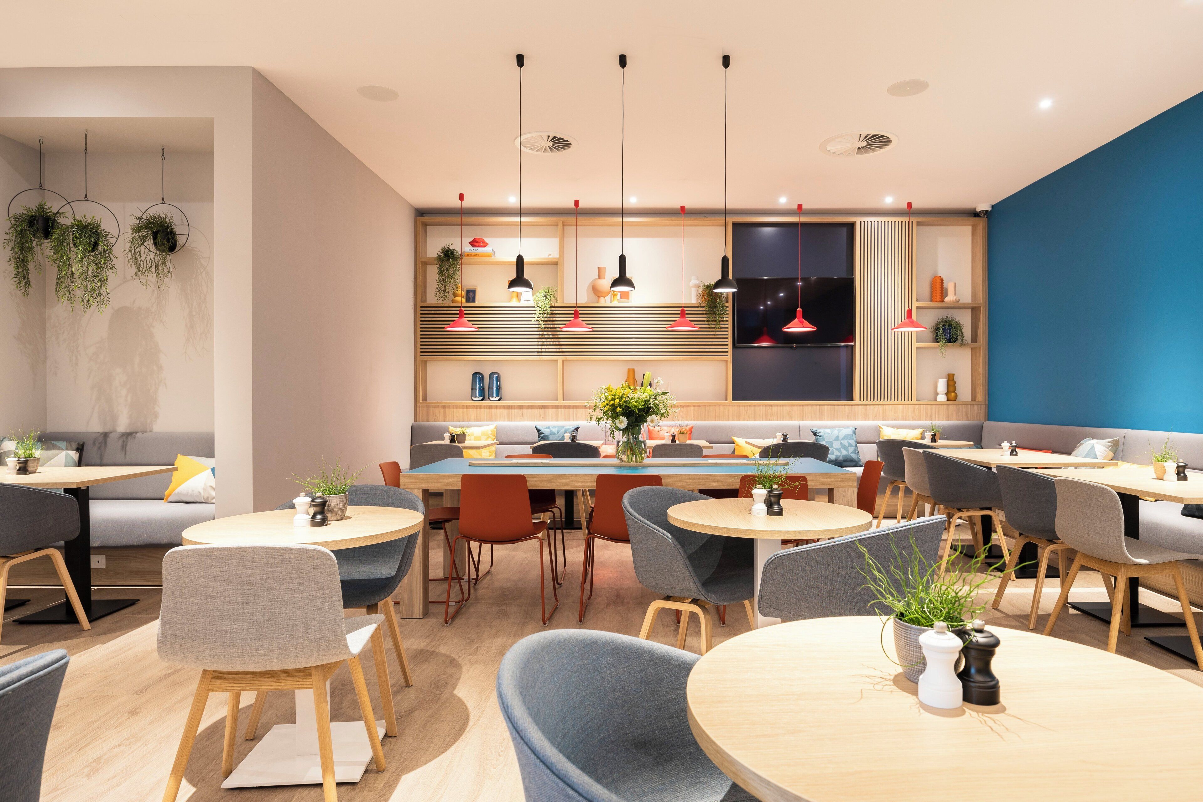 Un intérieur moderne avec des coins salon, des tables et des plantes suspendues.