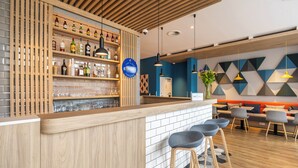 A modern bar area with wooden shelves, bar stools, and a blue sign. - Holiday Inn Express Antwerp City Centre by IHG (Antwerp)