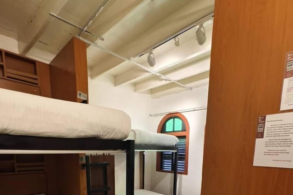 Camera con letto a castello, pareti in legno e finestra con persiane.