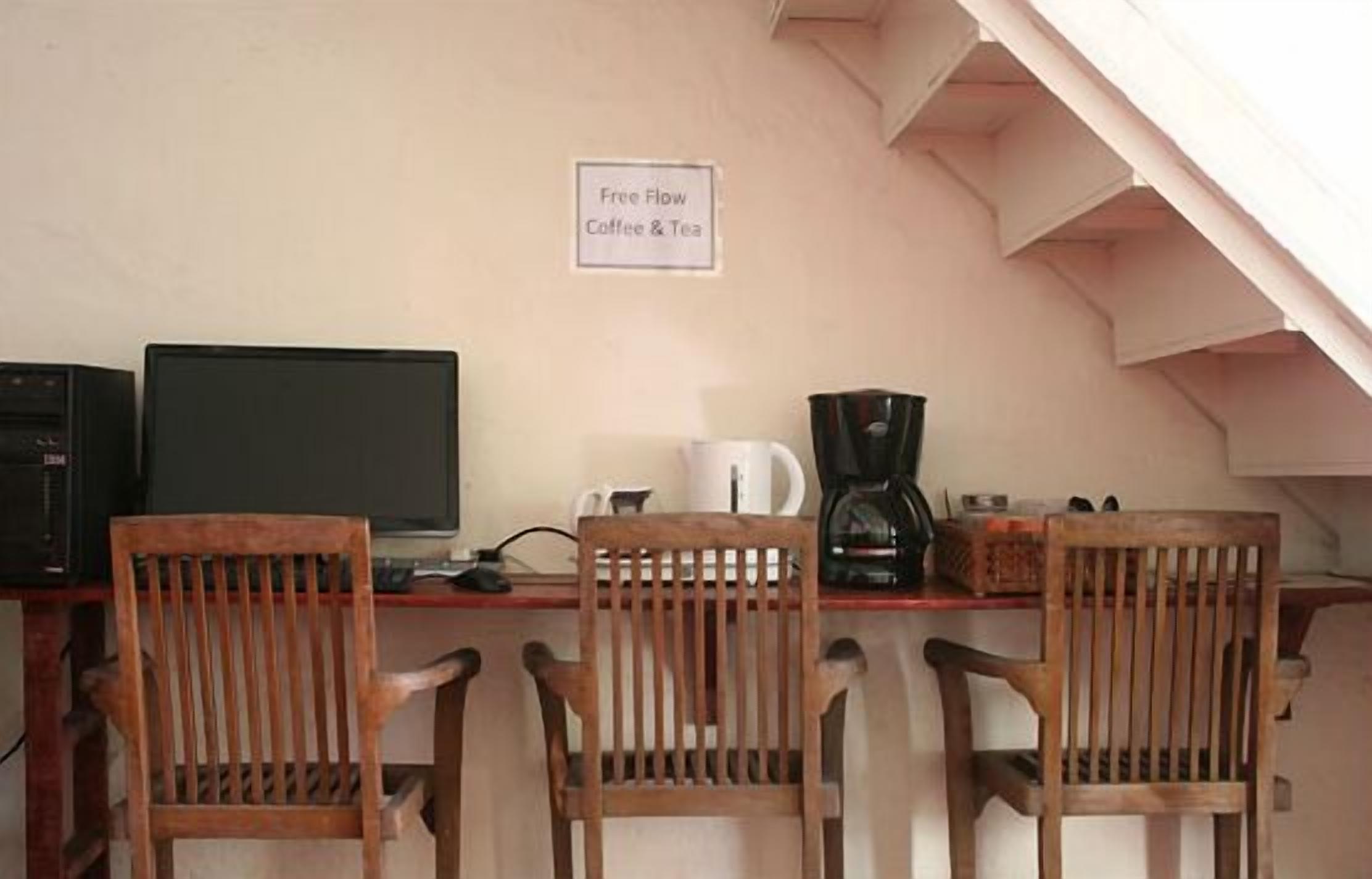 A workspace with a computer, coffee maker, and two wooden chairs. A sign on the wall reads "Free Flow Coffee & Tea."