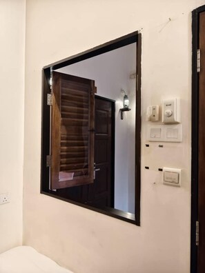 A room with a large mirror, a wooden door, and a wall-mounted light fixture. - Red Inn Court - Hostel (George Town)