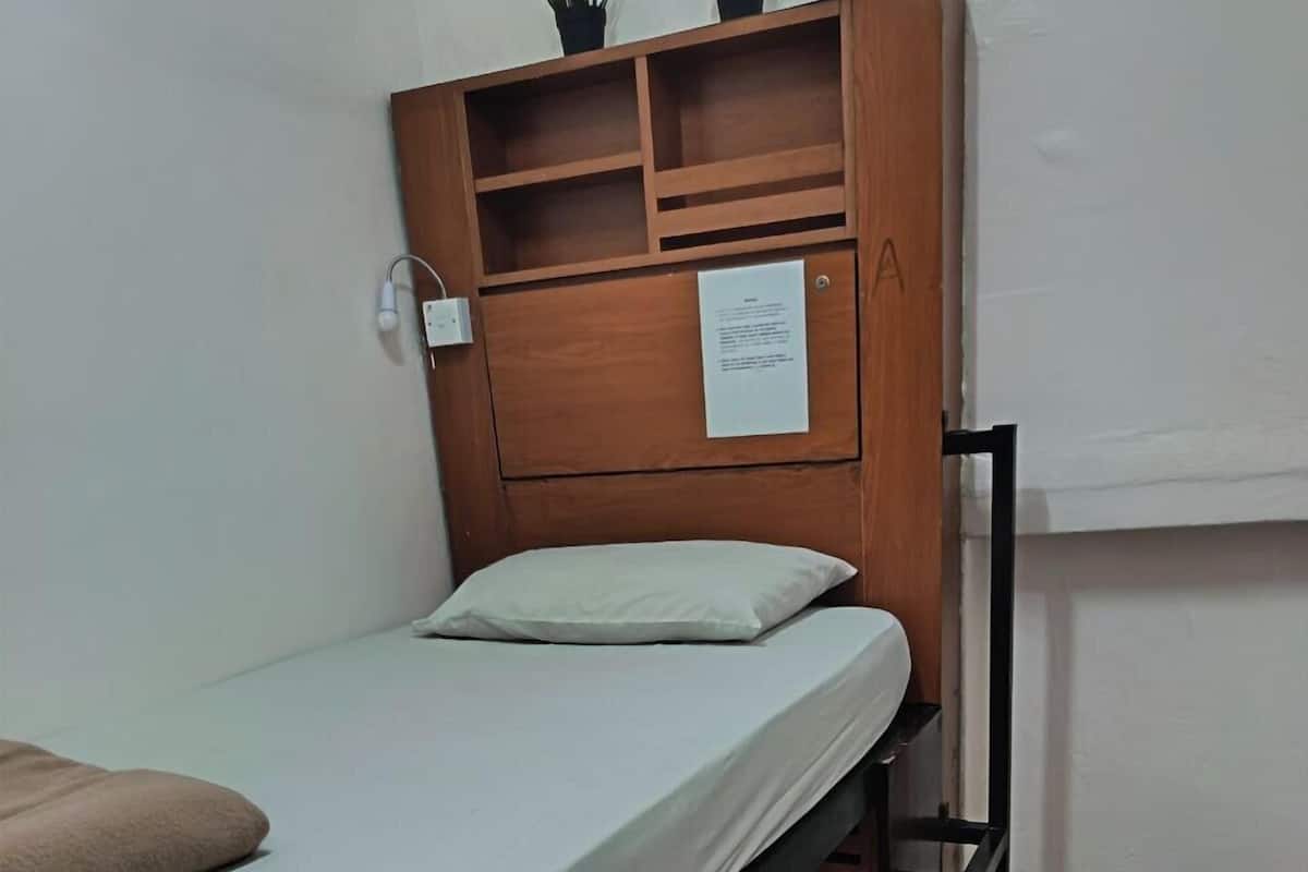 Un letto a castello con un poggiatesta in legno, un materasso bianco e un cuscino beige.