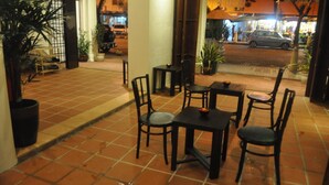 An outdoor patio with tiled flooring, black chairs, and tables.