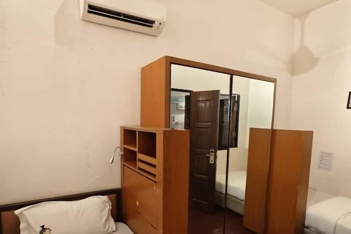 Una camera da letto con un letto, un armadio, uno specchio e un condizionatore d'aria.