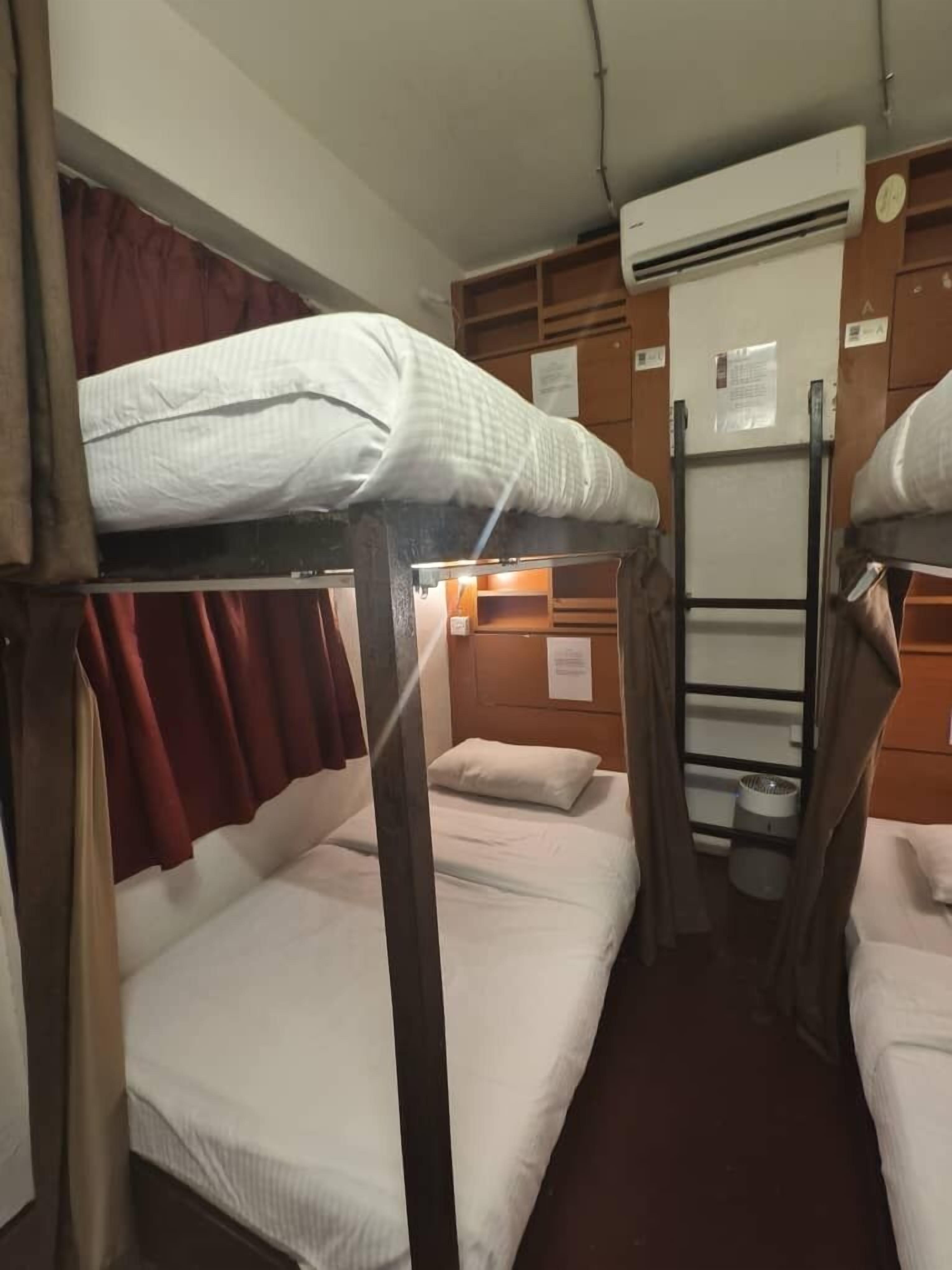 A bunk bed room with a wooden headboard, a small shelf, and a white air conditioning unit on the wall.