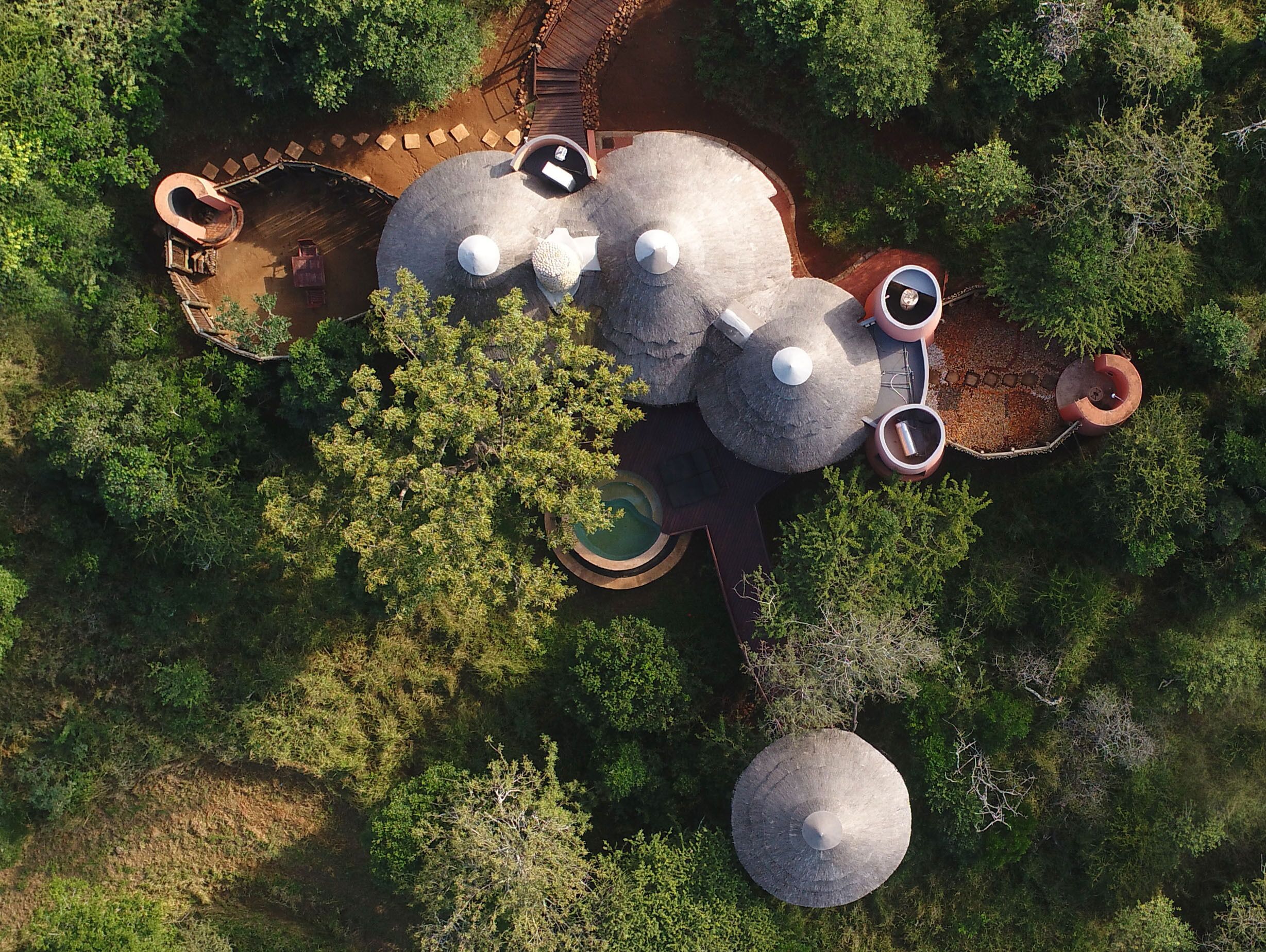 An aerial view of a resort with multiple circular structures, a pool area, and a wooden deck.