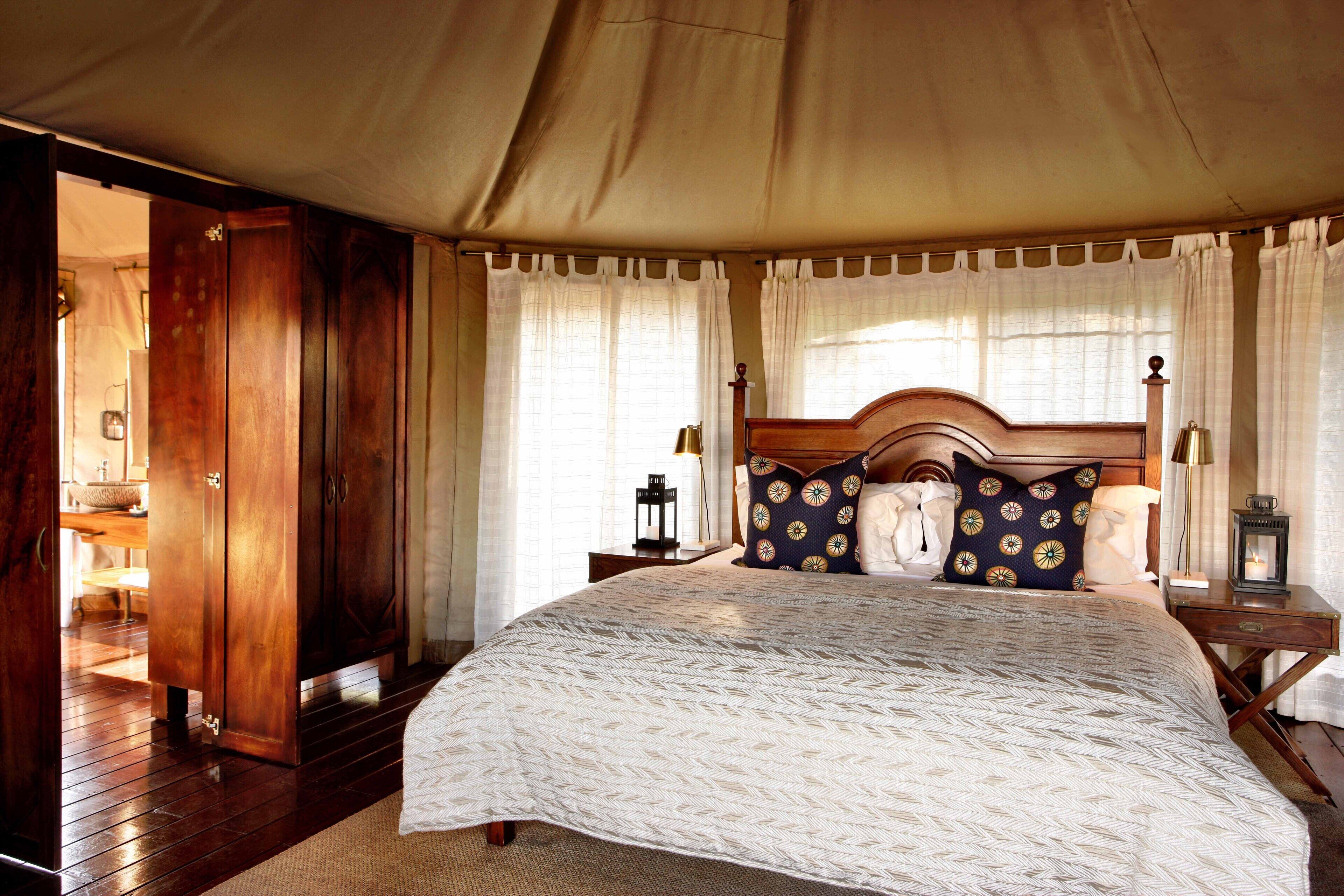 A spacious bedroom with a large bed, wooden wardrobe, and a canopy bed.