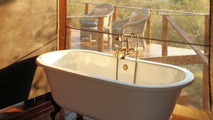 A tent with a bathtub, wicker chairs, and a view of the outdoors. - Thanda Safari (Hluhluwe)